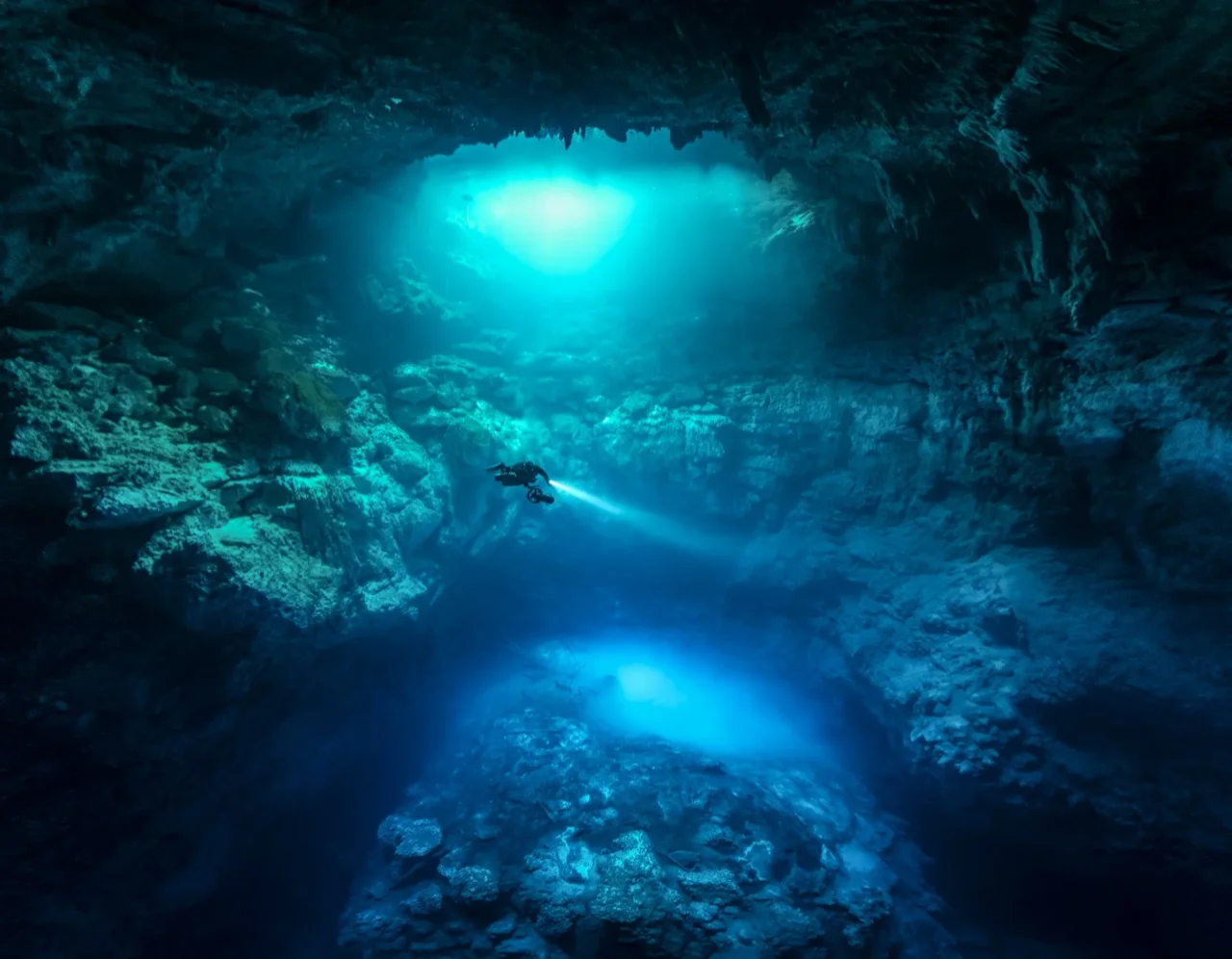 The Pit cenote deep cavern dive with light beams in Tulum Mexico