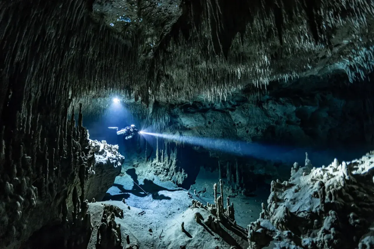 Certified cave diver using sidemount configuration to navigate a technical overhead environment in Mexico