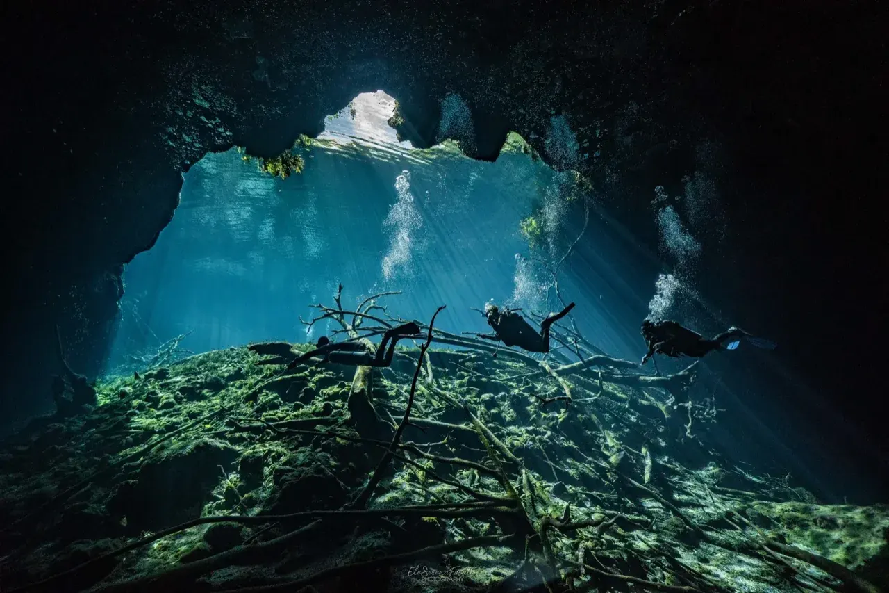 Scuba diver enjoying guided cenote cavern diving with light beams in Tulum, Mexico