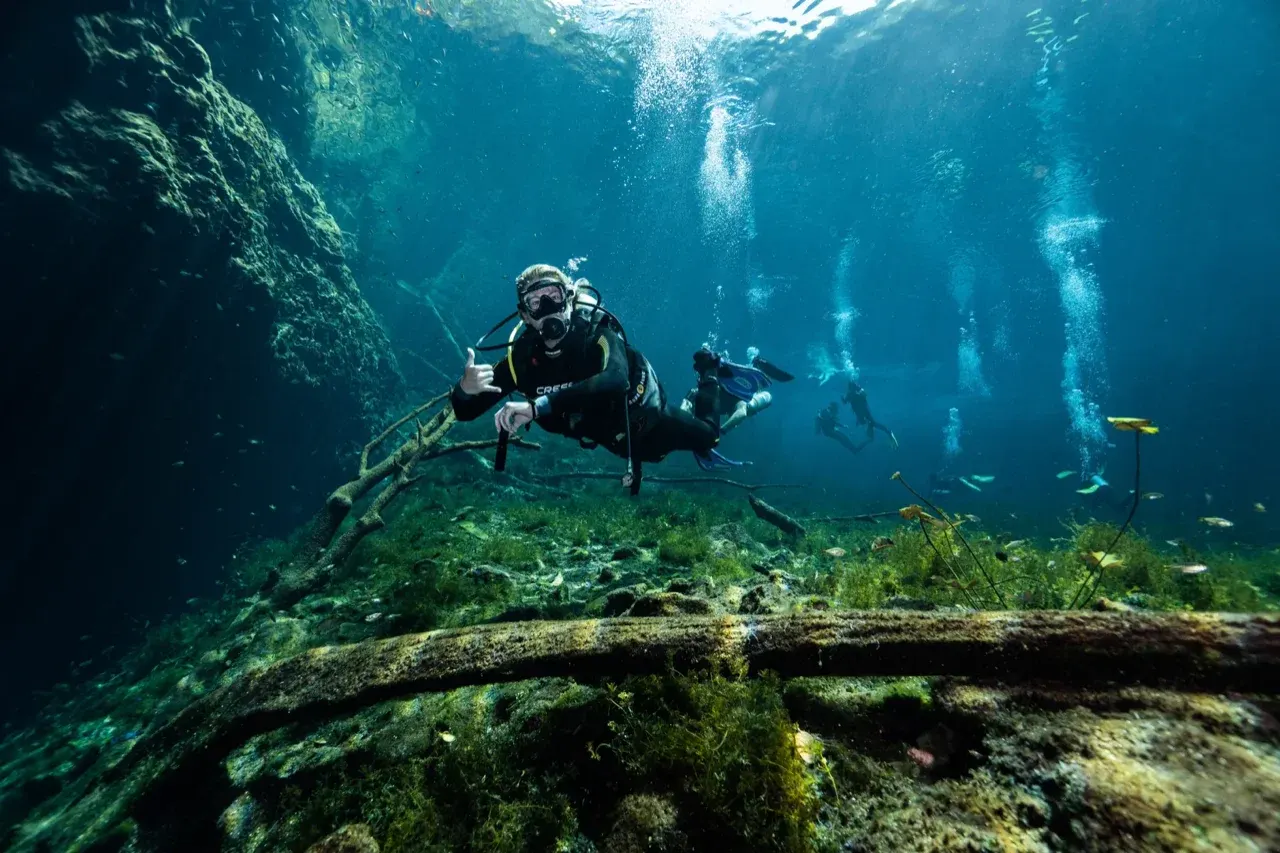 Beginner diver practicing buoyancy control during a PADI Open Water course in a clear water cenote